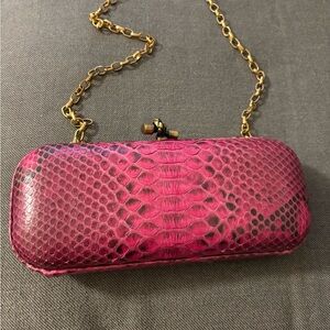 fuchsia-colored python-embossed  clutch with a gold-chain strap.
